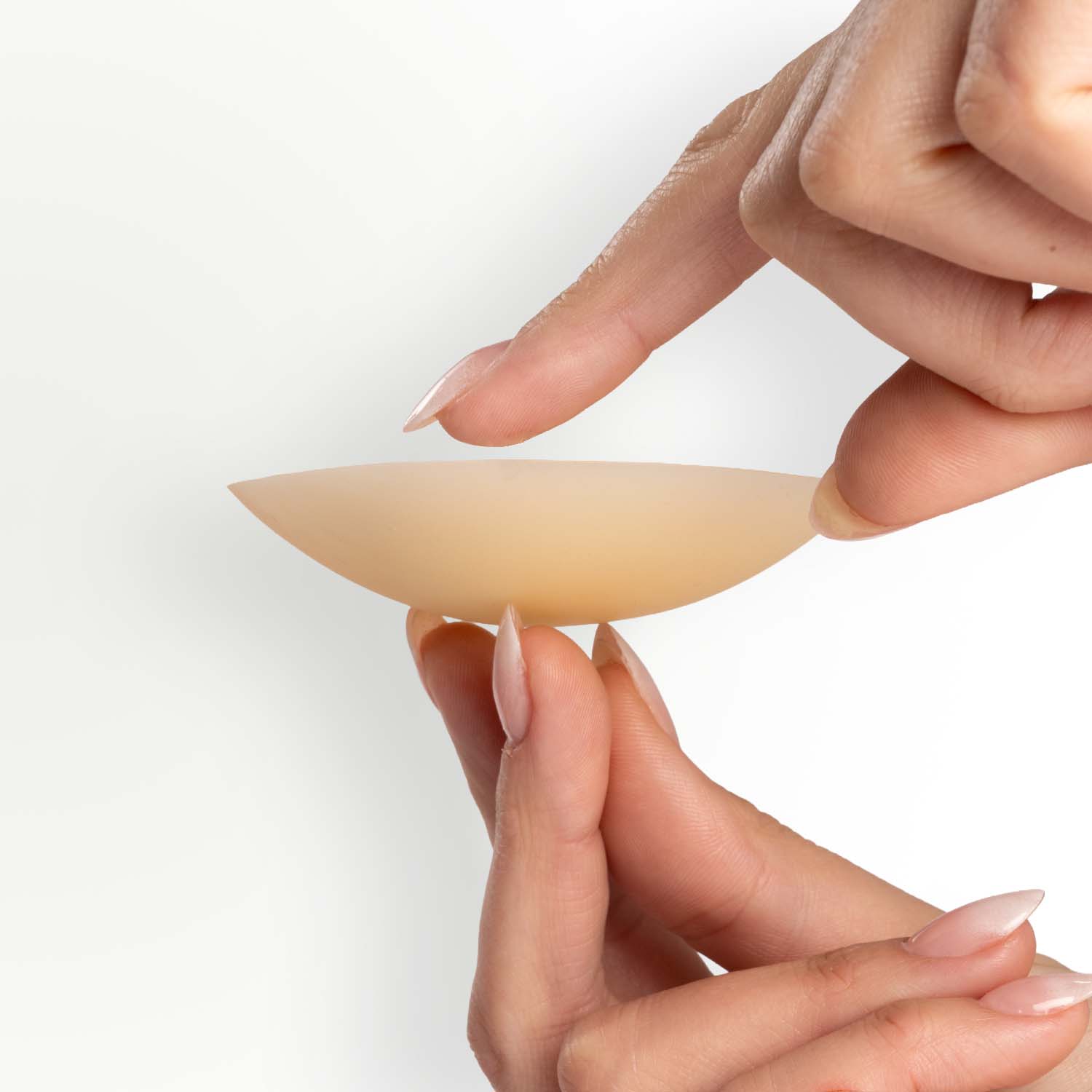 Hand holding one Bare and Basic vanish premium reusable nipple cover on a white background